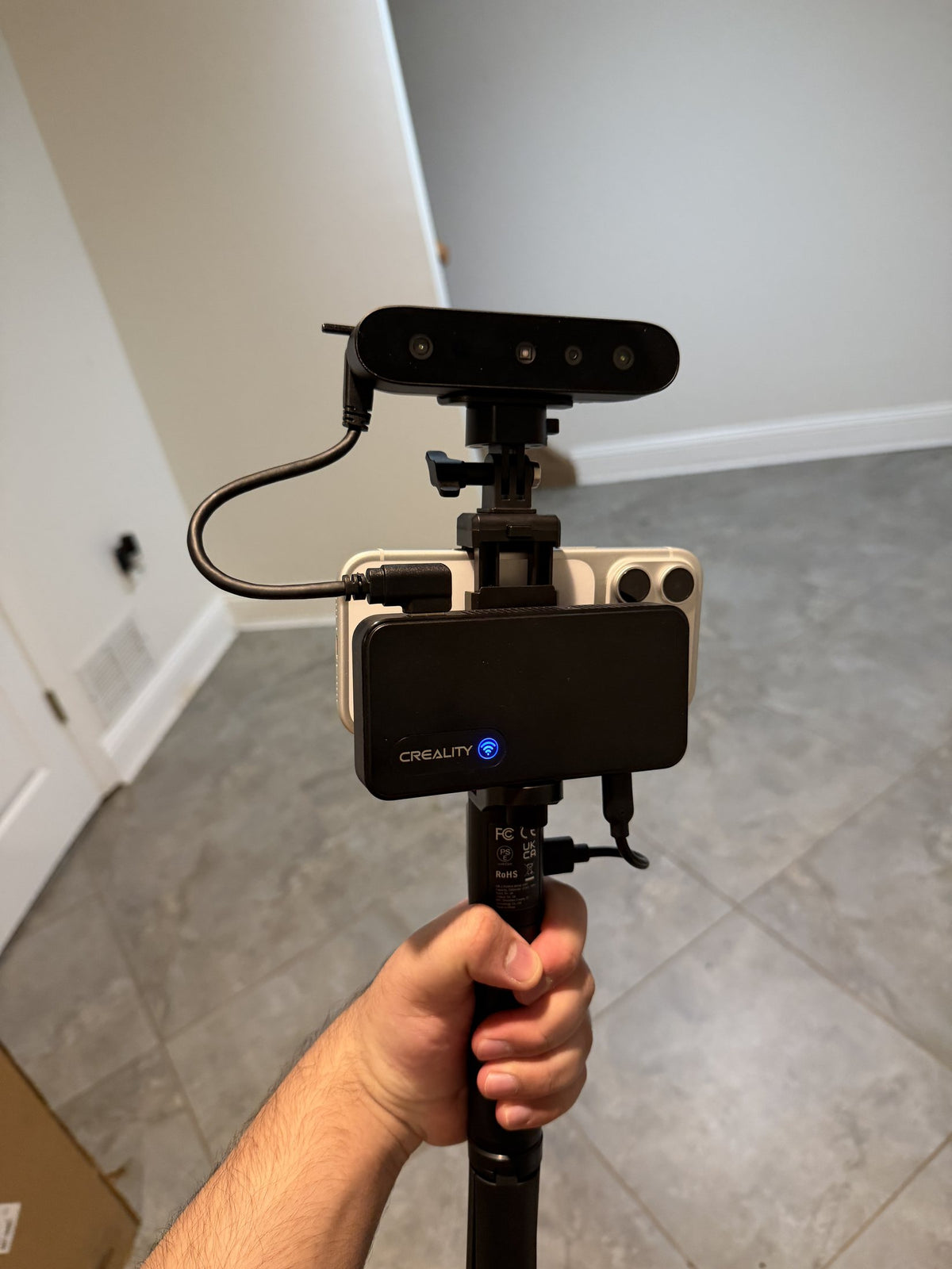 Handheld 3D scanner on a grip, with a phone mounted behind it