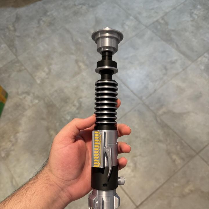 Silver and black prop saber hilt printed in silk PLA, held in a hand