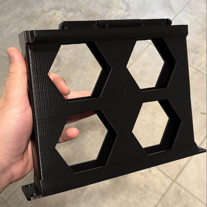 Black PETG rack frame with hexagon cut-outs, held in a hand